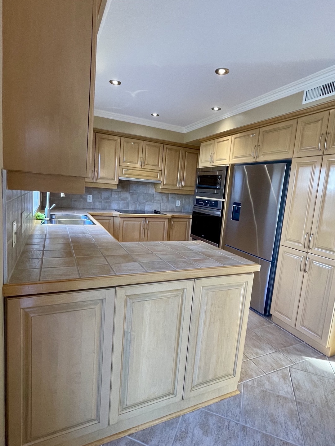 Cuisine de bois refinie ton clair, comptoir de ceramique, peninsule et electromenagers inox